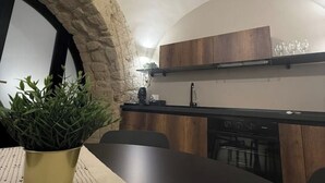 A modern kitchen with wooden cabinets, a built-in oven, and a stone archway.