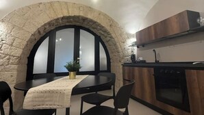 A kitchen with a stone arch, a dining table with chairs, and a modern oven.