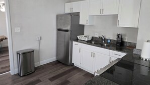 Eine moderne Küche mit weißen Schränken, einem Edelstahlkühlschrank, einer Granit Arbeitsplatte und einer schwarzen Kochstelle.