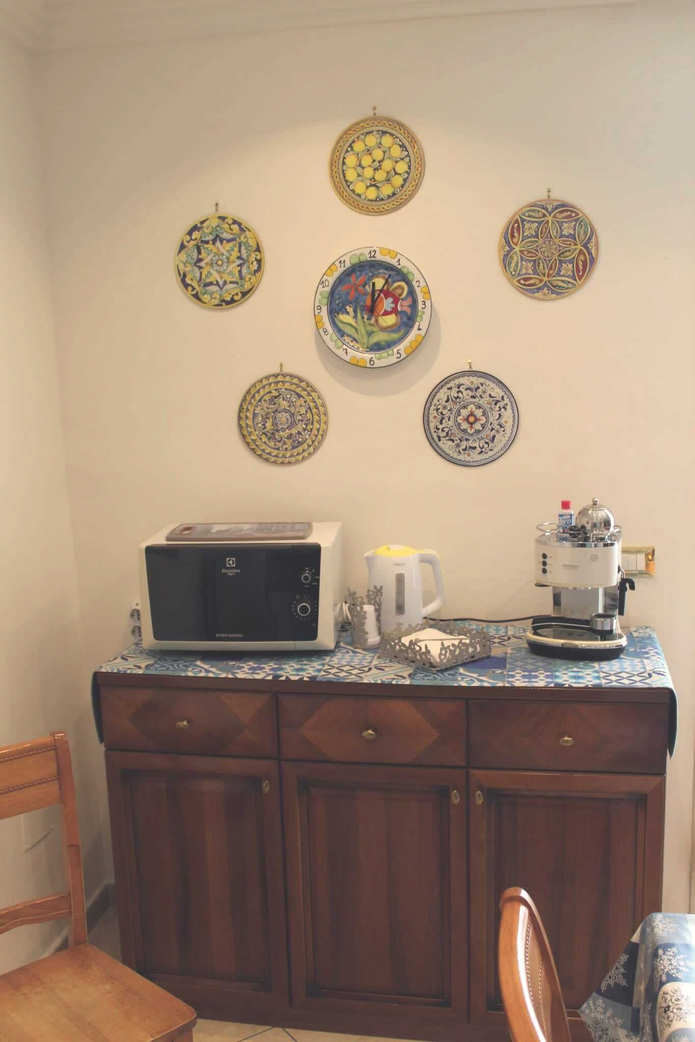 A kitchen with a microwave, coffee maker, and decorative plates on the wall.
