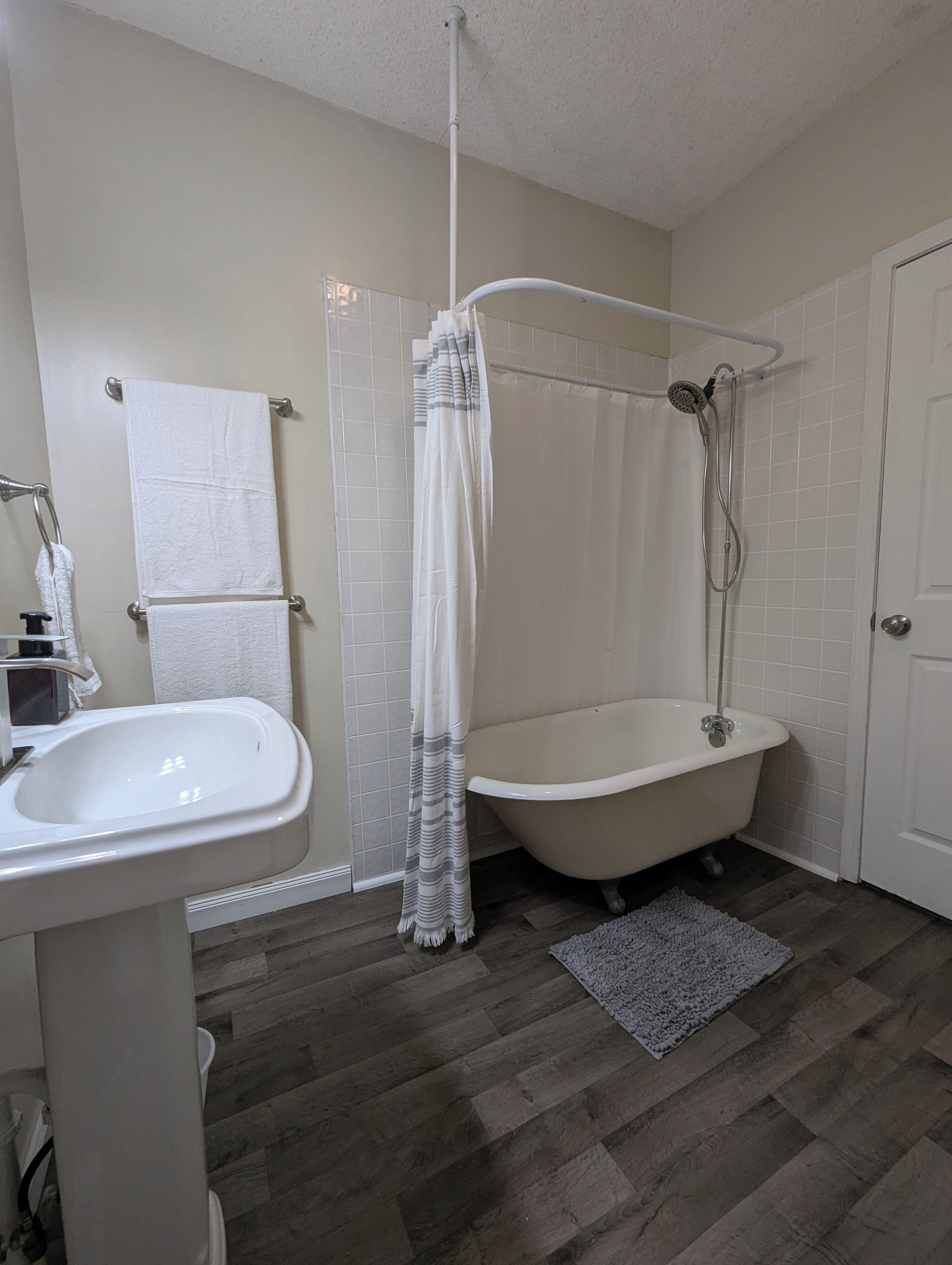 Une salle de bain avec un lavabo blanc, une baignoire, une douche et un porte-serviettes.