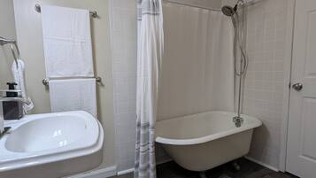 Une salle de bain avec un lavabo blanc, une baignoire, une douche et un porte-serviettes.