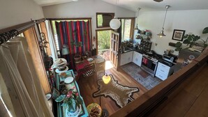 A spacious kitchen with modern appliances, a dining area with a wooden table, and a view of the outdoors through a large window. - The Loft at Topanga Canyon: Cottage Retreat with Trails, Creek & Mountain View (Topanga)