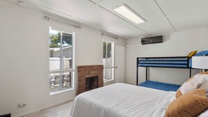 A bedroom with a bunk bed, a fireplace, and large windows. - Modern Coastal Retreat – 3BR Gem in Long Beach (Long Beach)