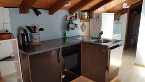 A compact kitchen with wooden beams, a built-in dishwasher, and a sink.