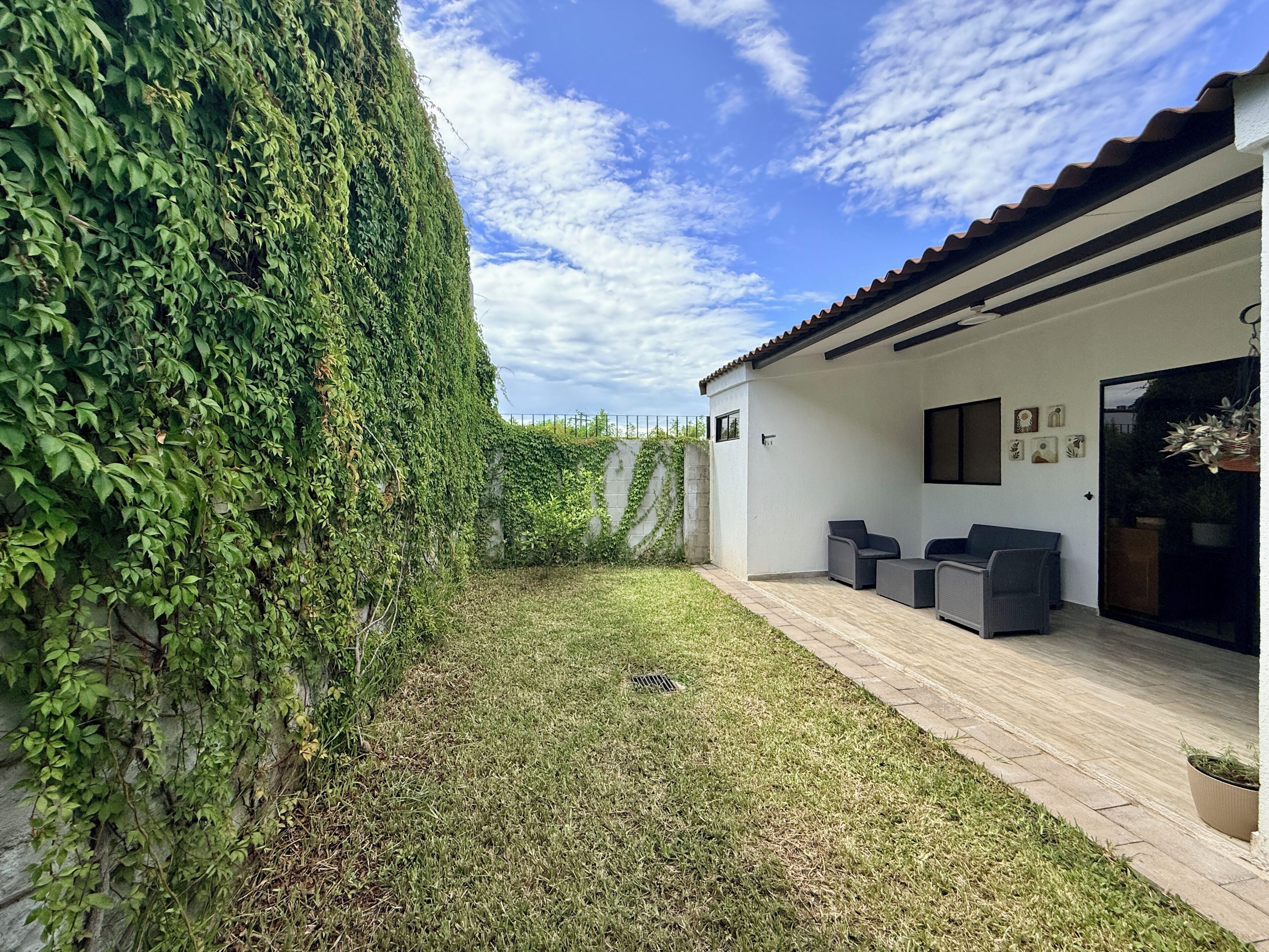 Un patio extérieur moderne avec un mur blanc, une terrasse en bois et un espace salon comprenant deux canapés.