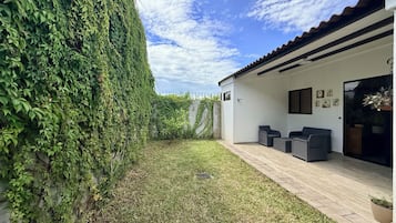 Un patio extérieur moderne avec un mur blanc, une terrasse en bois et un espace salon comprenant deux canapés.