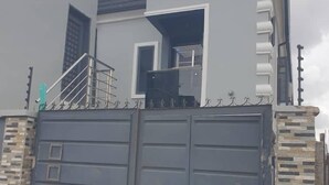 En lukket boligejendom med en toetages bygning, en balkon og en synlig trappe.