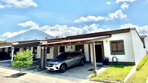 A modern two-story house with a covered garage, a parked car, and a small tree in the front yard. - Beautiful 3-bedroom house in the most exclusive zone of  Sn Miguel with WiFi, AC (San Miguel)