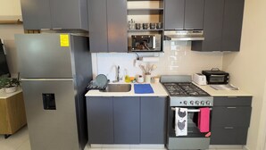 A modern kitchen with grey cabinets, a stainless steel refrigerator, a microwave, a stove, and a sink. - Beautiful 3-bedroom house in the most exclusive zone of  Sn Miguel with WiFi, AC (San Miguel)