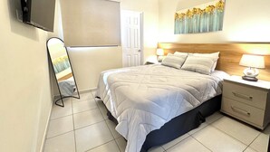 A neatly arranged bedroom with a bed, bedside tables, a TV mounted on the wall, and a ceiling fan. - Beautiful 3-bedroom house in the most exclusive zone of  Sn Miguel with WiFi, AC (San Miguel)