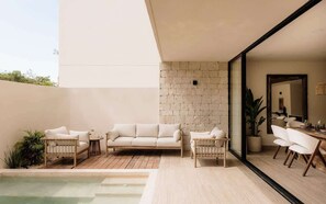 A modern outdoor living space with a pool, a white sofa, and a dining area.