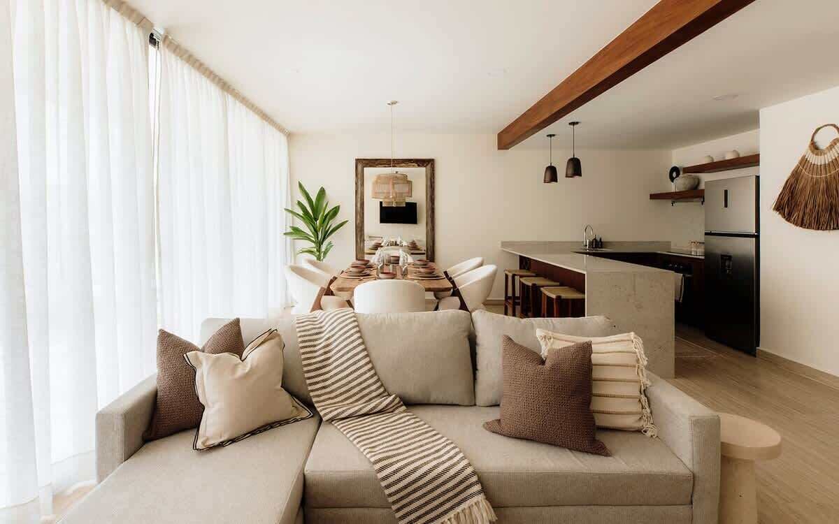 A modern living room with a sofa, a dining table, and a kitchen area.