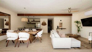 A modern living room with a sofa, dining table, chairs, and a TV mounted on the wall. - Huemac Tropical Paradise Private Pool Beach Club (Tulum)