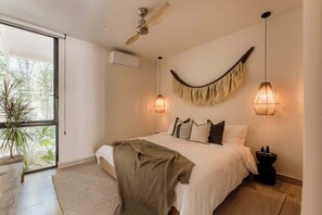 A bedroom with a bed, ceiling fan, wall-mounted lights, and a potted plant.
