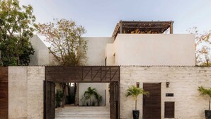 A gated entrance with a wooden pergola, a brick wall, and a number sign indicating the location. - Casa Chacalaca Perfect Bachelorette Villa (Tulum)