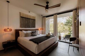 A bedroom with a bed, bedside lamp, ceiling fan, and a view of the outdoors. - Casa Chacalaca Perfect Bachelorette Villa (Tulum)