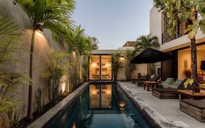 Un espace piscine comprenant des chaises longues, une petite piscine et un bâtiment doté d’un balcon.