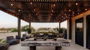 An outdoor patio with a wooden pergola, seating, and a central table. - Casa Chacalaca Perfect Bachelorette Villa (Tulum)