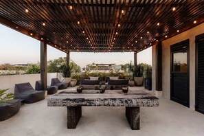 An outdoor patio with a wooden pergola, seating, and a central table. - Casa Chacalaca Perfect Bachelorette Villa (Tulum)