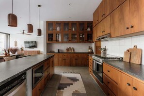 A modern kitchen with wooden cabinets, a central island, and pendant lighting.