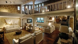 Amplio espacio tipo loft con techo alto, paredes de piedra y un balcón.