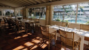 Un restaurante con terraza, ventanas amplias y vistas a una piscina.