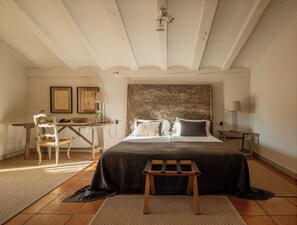 Ein Schlafzimmer mit Bett, Nachttisch, Lampe, Stuhl und einem rustikalen Kopfteil.