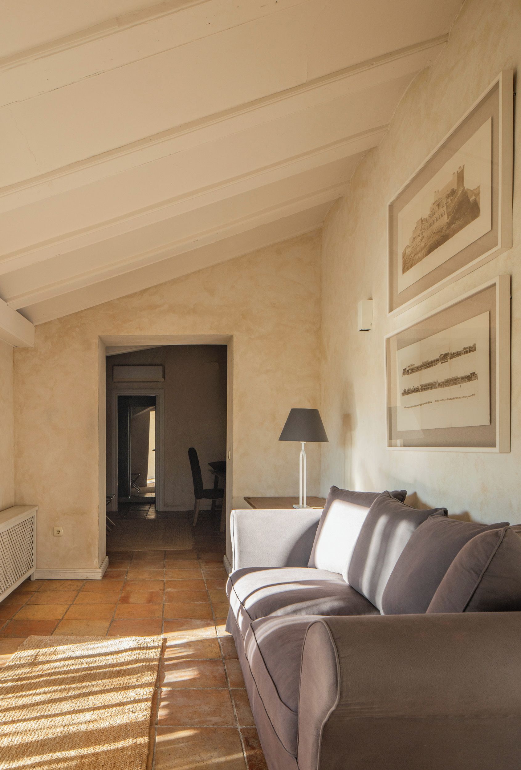 Una sala de estar con un sofá, una lámpara y cuadros en la pared.