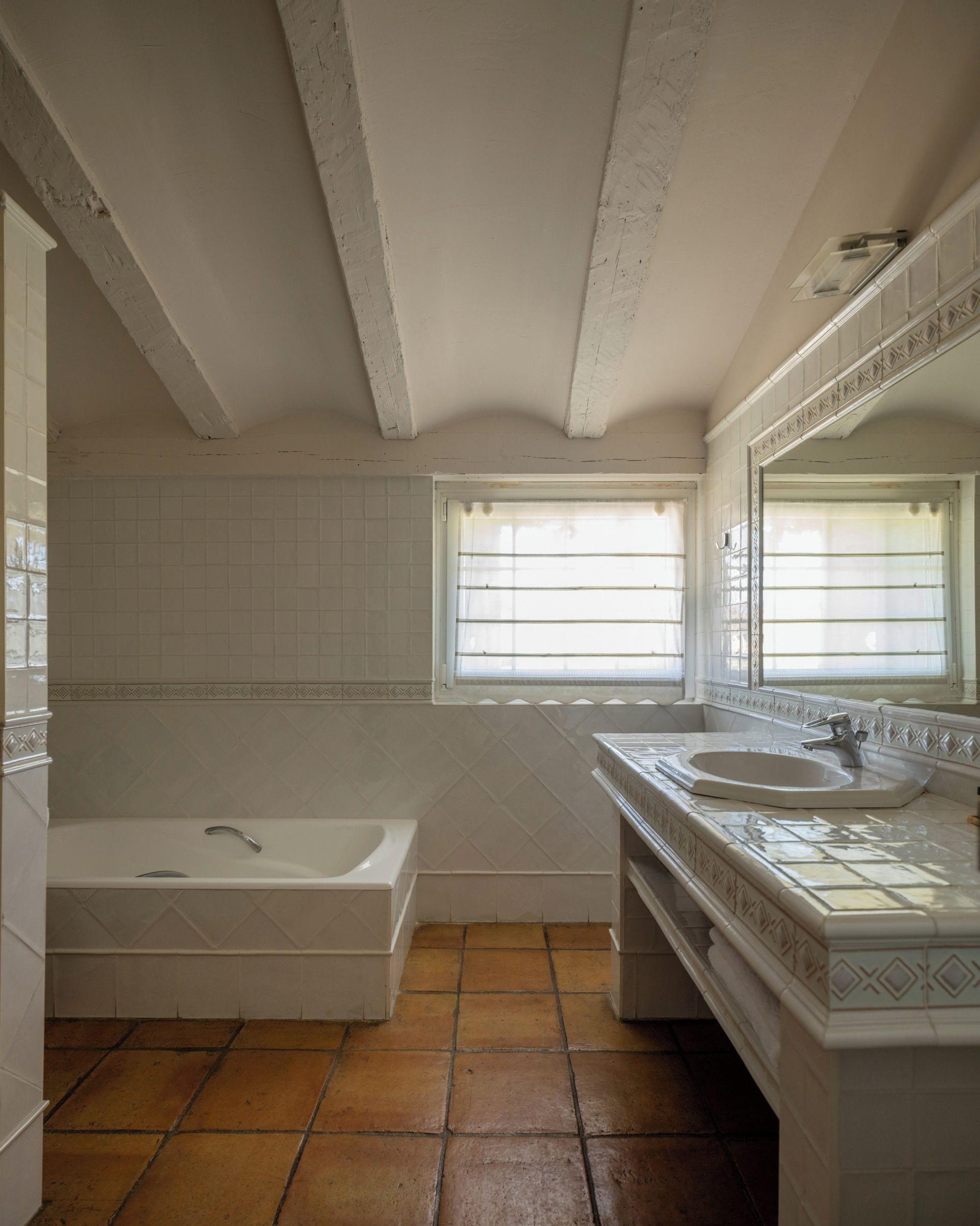 A bathroom with a bathtub, a sink, and a window with blinds.