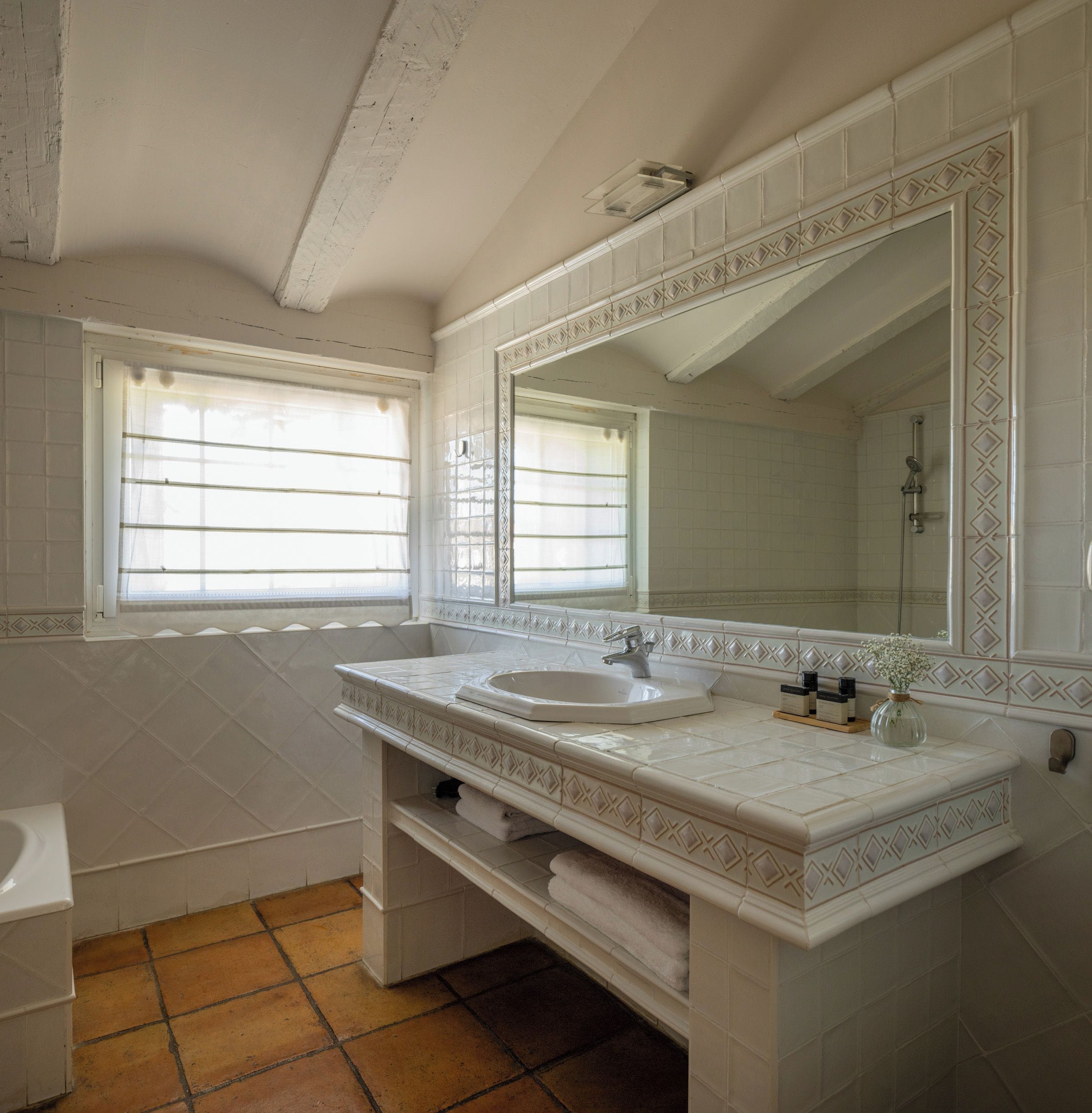 Een badkamer met een dubbele wastafel, een grote spiegel en een raam met jaloezieën.