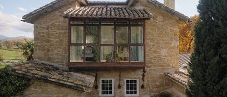 A stone building with a large window and a small balcony.