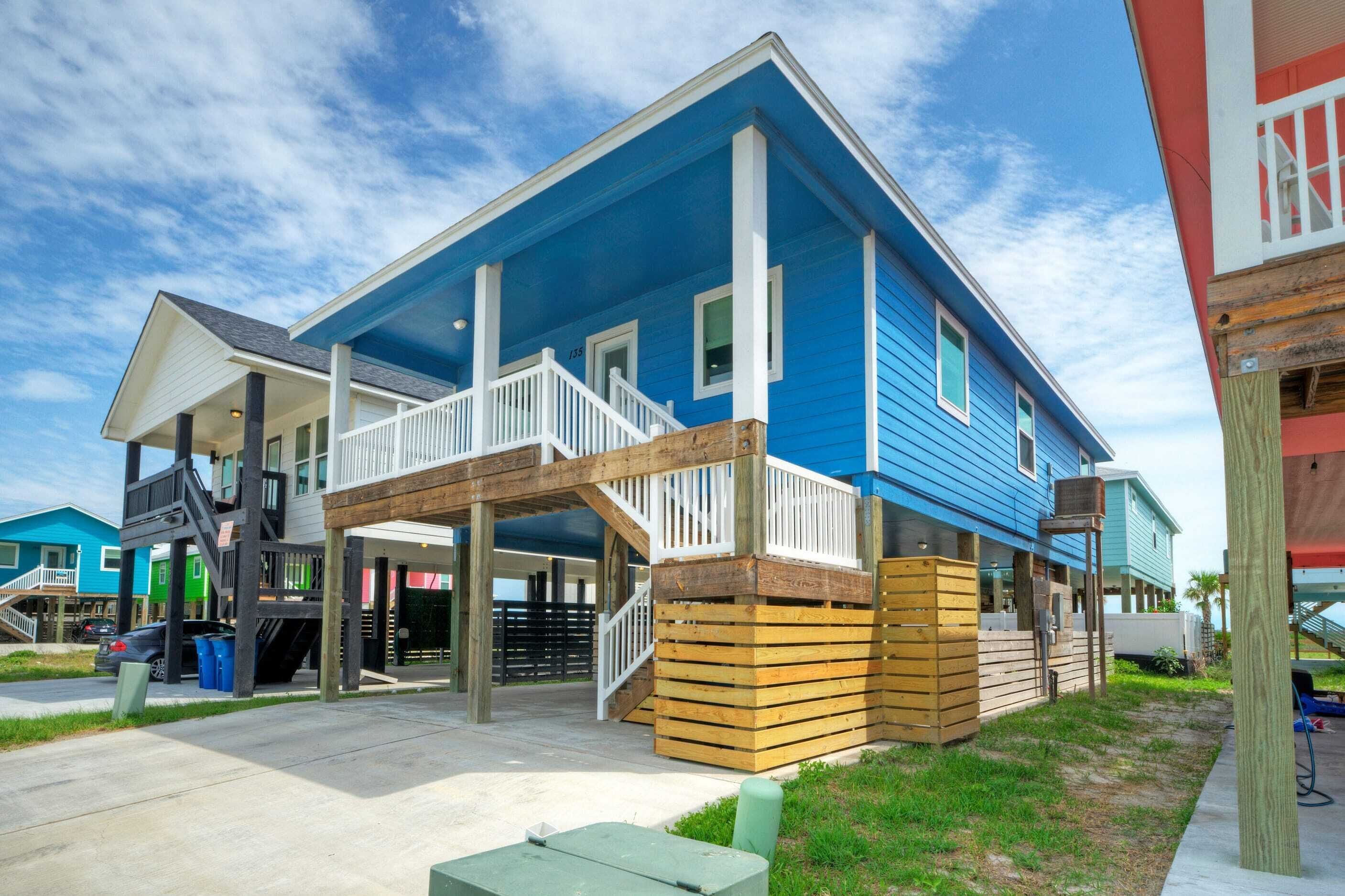 A two-story building with a blue exterior, a covered porch, and a wooden deck.