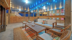 A cozy, well-lit wooden interior with a sofa, chairs, and a staircase.
