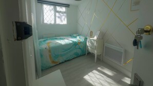 A bedroom with a bed, a desk, a radiator, and a window with blinds. - Spacious 4BR Bungalow with Parking Near Spider-Man Filming Locations (London)