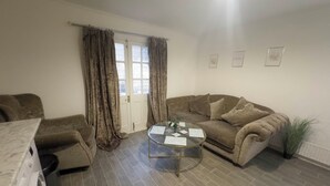 A living room with a sofa, a coffee table, and a washing machine. - Spacious 4BR Bungalow with Parking Near Spider-Man Filming Locations (London)