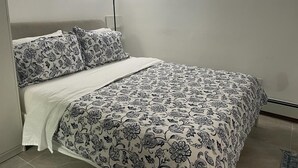 A bedroom with a bed, a bedside lamp, and a patterned bedspread. - 2-bedroom, 1 Bath apartment in gorgeous Roslyn with Washer Dryer in unit (Roslyn)