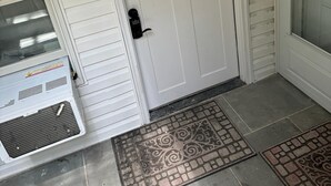 A white door with a window, a small porch area with a metal grate, and a doormat. - 2-bedroom, 1 Bath apartment in gorgeous Roslyn with Washer Dryer in unit (Roslyn)