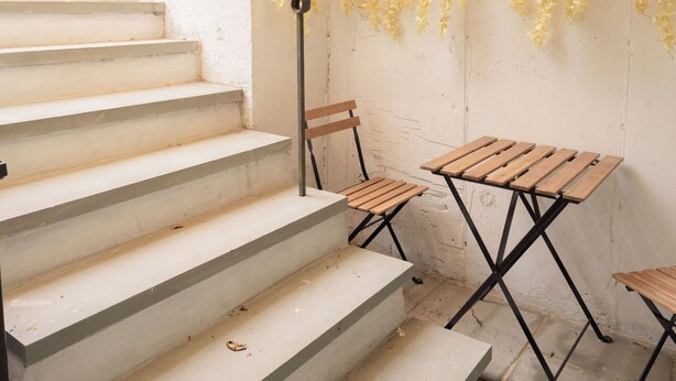 A staircase with a wooden table and chairs, a hanging plant, and a view of greenery outside. - 2-bedroom, 1 Bath apartment in gorgeous Roslyn with Washer Dryer in unit (Roslyn)