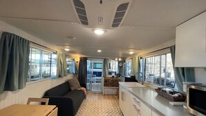 Interior compacto de una caravana con kitchenette, zona de estar y una pequeña mesa de comedor.