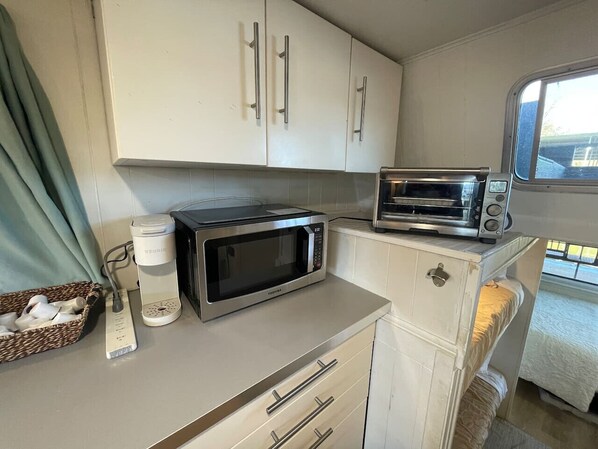 A compact kitchenette with a microwave, toaster, and a small refrigerator.