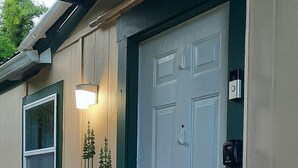 Une terrasse en bois avec une porte blanche et un pot de fleurs.