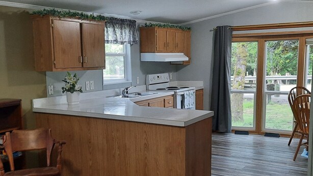 Une cuisine avec des meubles en bois, un îlot central, une fenêtre et une vue sur l’extérieur.