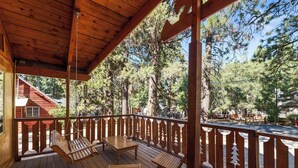 Eine Holzterrasse mit Schaukelstuhl, Tisch und Bank.