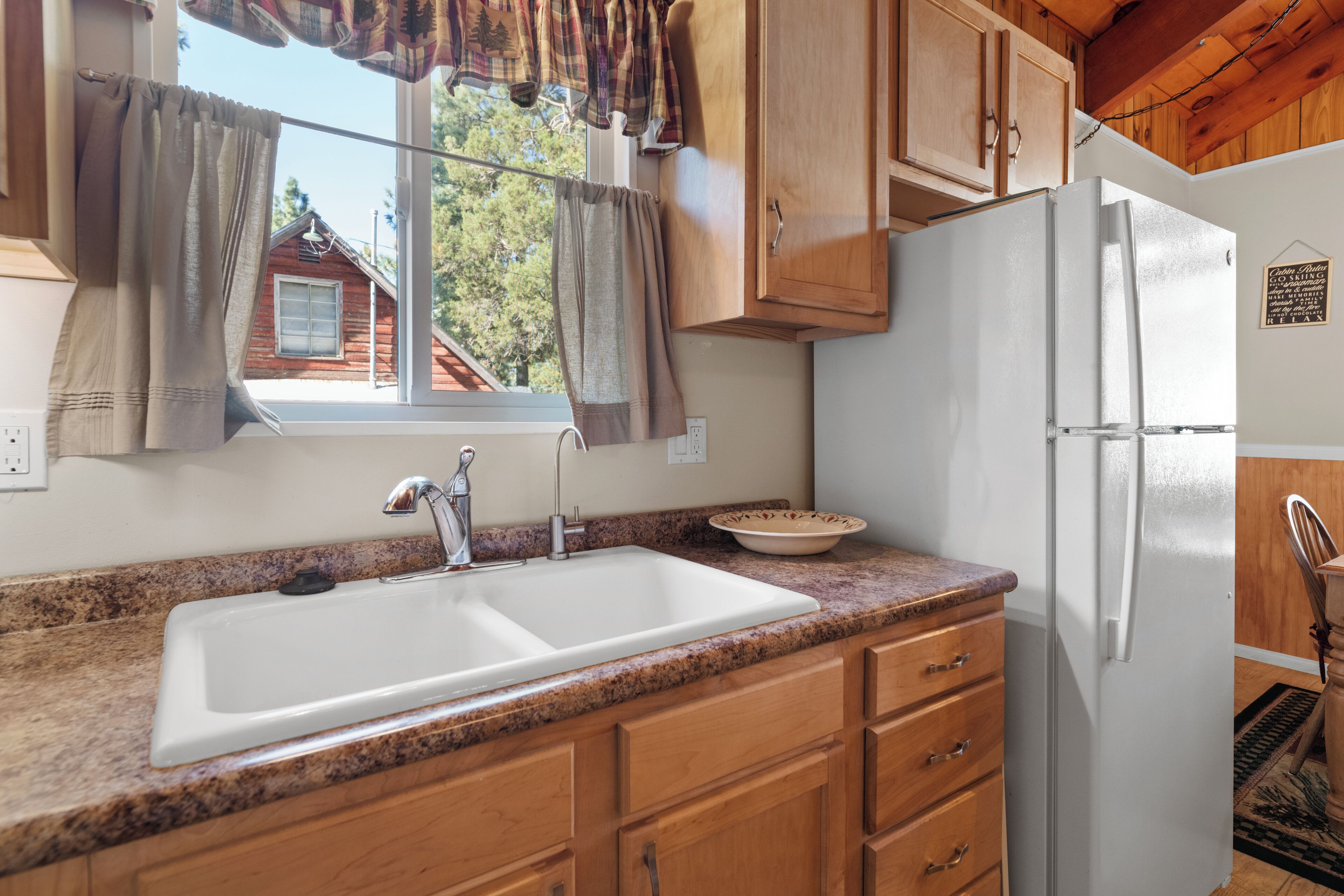 A kitchen with wooden cabinets, a white sink, and a refrigerator.