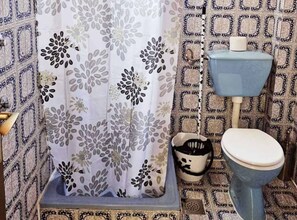 A bathroom with a patterned shower curtain, a toilet, and a sink with a black and white pitcher.