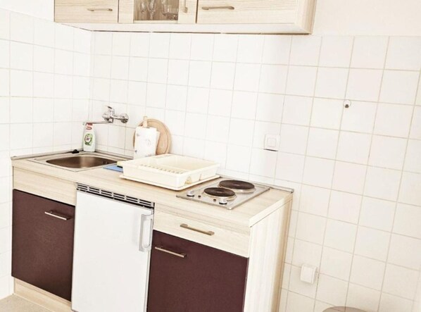 A compact kitchen with a sink, stove, and cabinets.