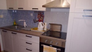 Een keuken met een spoelbak, fornuis, oven en waterkoker.