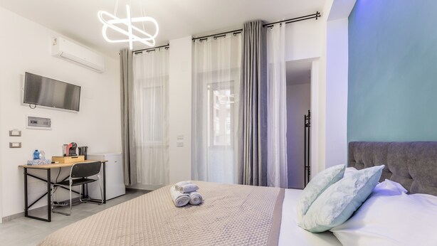 Une chambre d’hôtel équipée d’un lit, d’un bureau, d’une télévision et d’un espace douche.