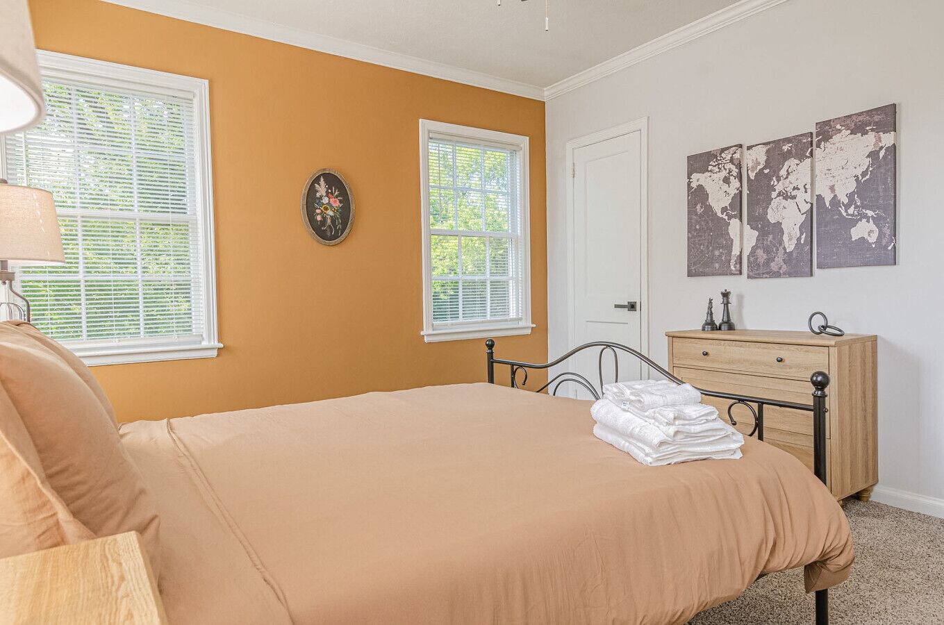 Une chambre à coucher avec un lit, une commode et une œuvre d’art représentant une carte du monde accrochée au mur.